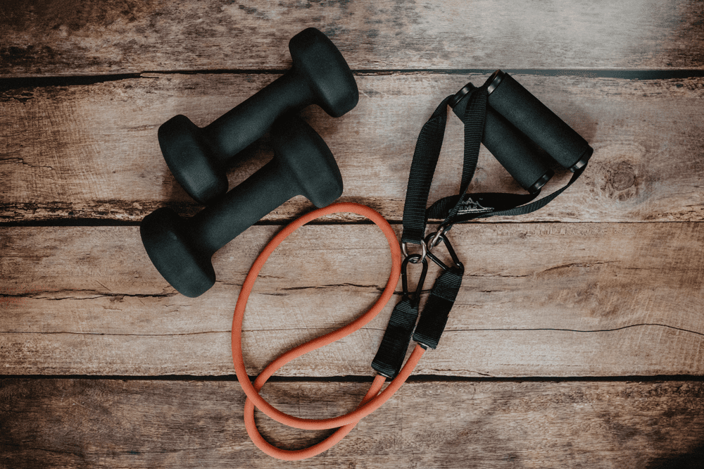 A pair of dumbbells and a jump rope on top of a wooden floor.