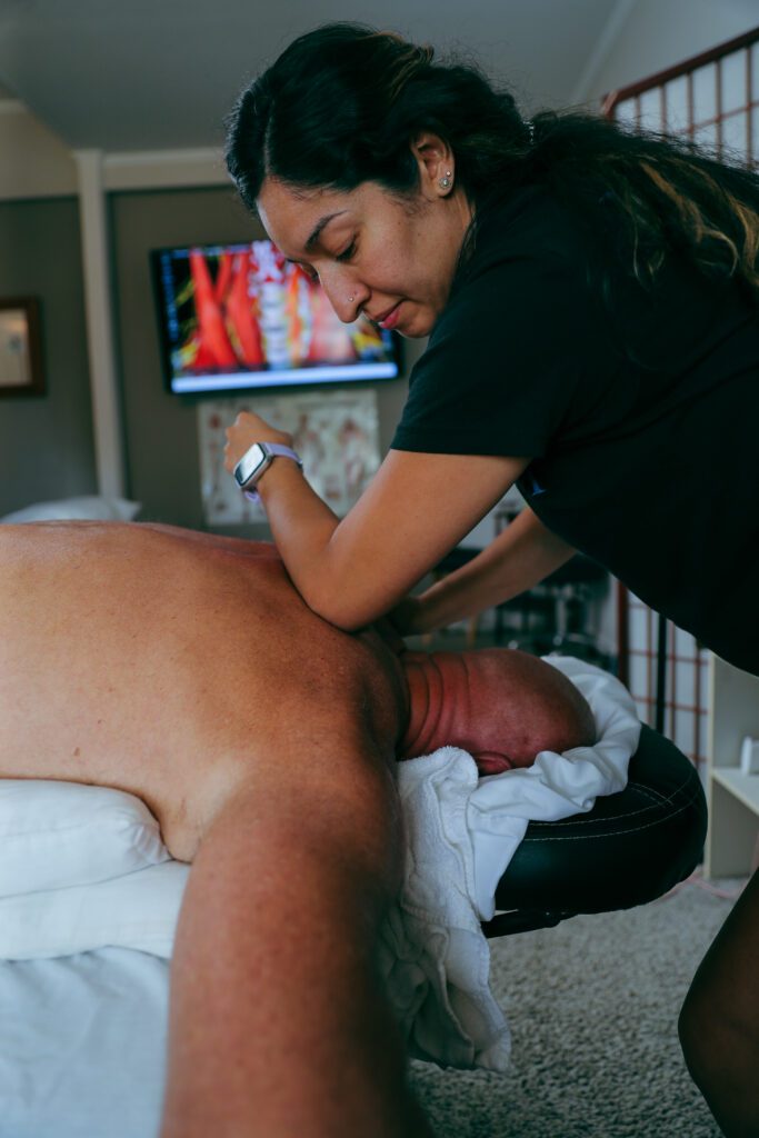Person receiving back massage from therapist.