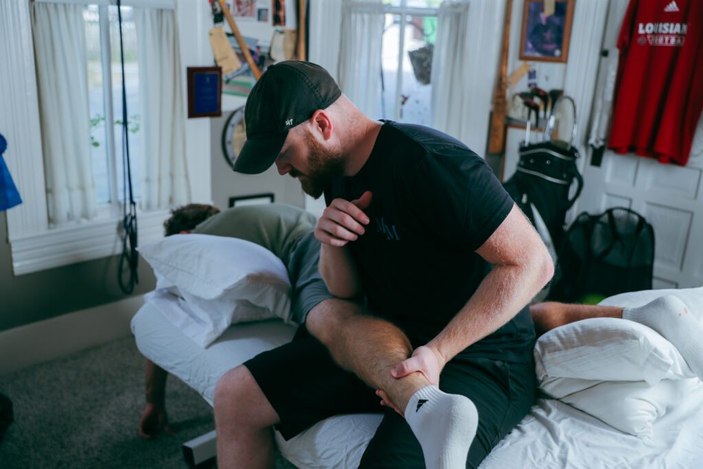 Therapist stretching patient's leg on table.