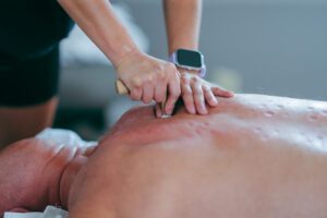 Person receiving back massage with wooden tool.