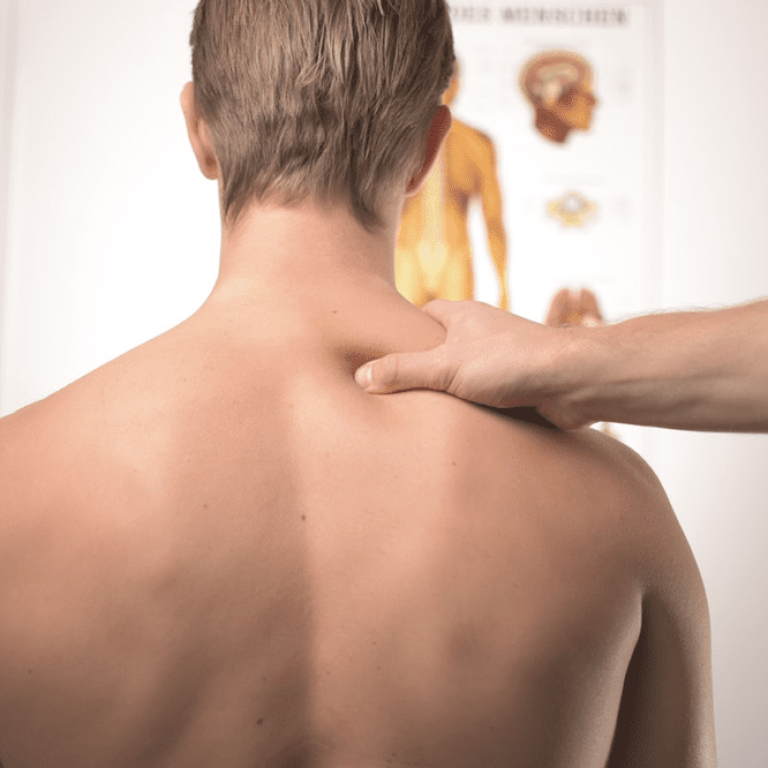 A person is holding their back while another person touches the shoulder.