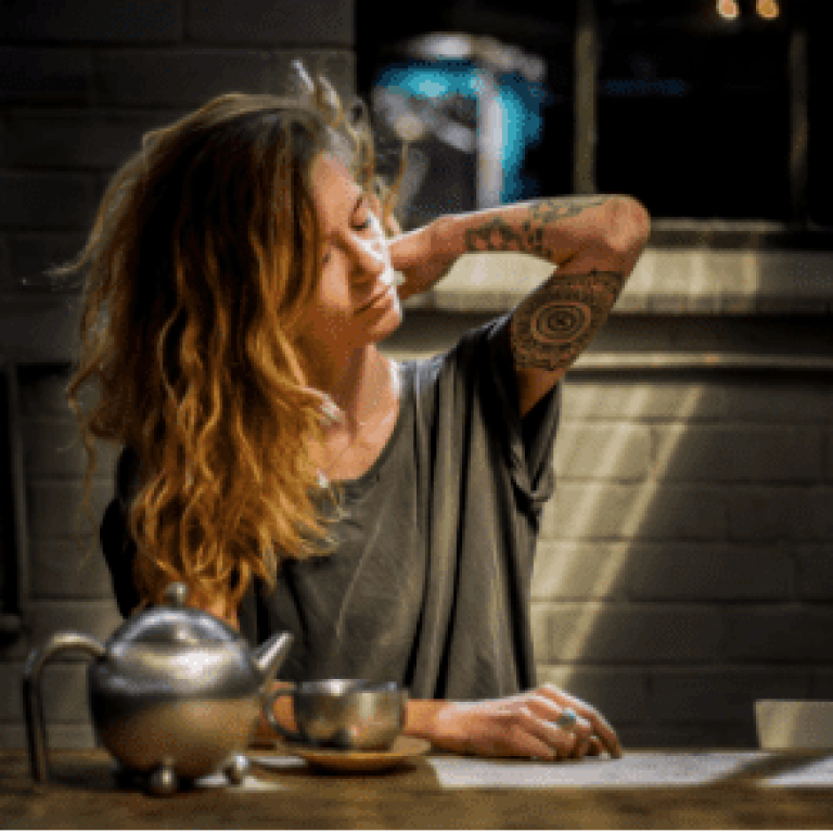 A woman sitting at a table with her hand on her face.